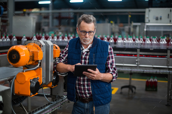 Factory Worker Using Digital Tablet Next To Production Line